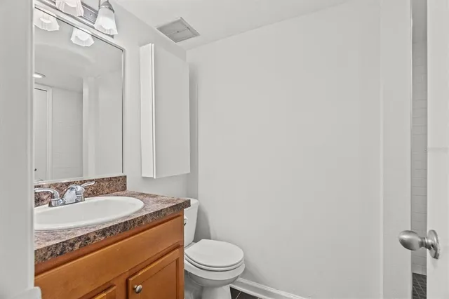 a bathroom with a granite countertop sink toilet and a mirror