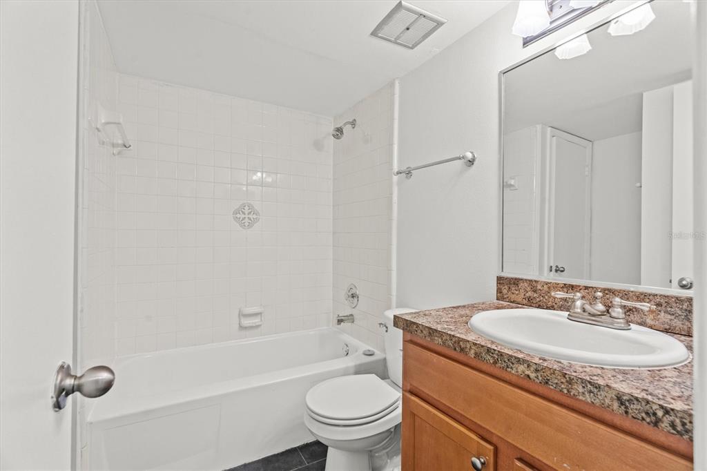 2992 Plaza Terrace Drive, Unit 2992 Orlando, FL 32803 - Photo 14 of 31 a bathroom with a granite countertop sink a toilet a mirror and shower