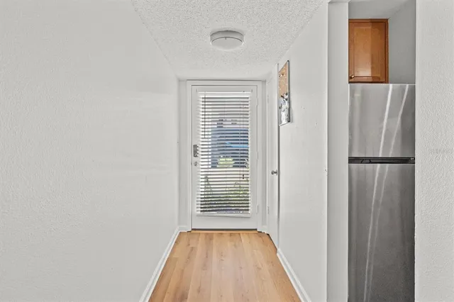 a view of a hallway with wooden floor and a bathroom