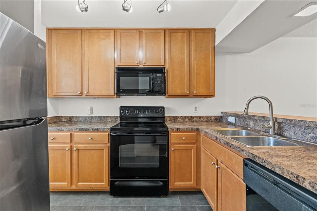 2992 Plaza Terrace Drive, Unit 2992 Orlando, FL 32803 - Photo 5 of 31 a kitchen with granite countertop a sink stove and microwave