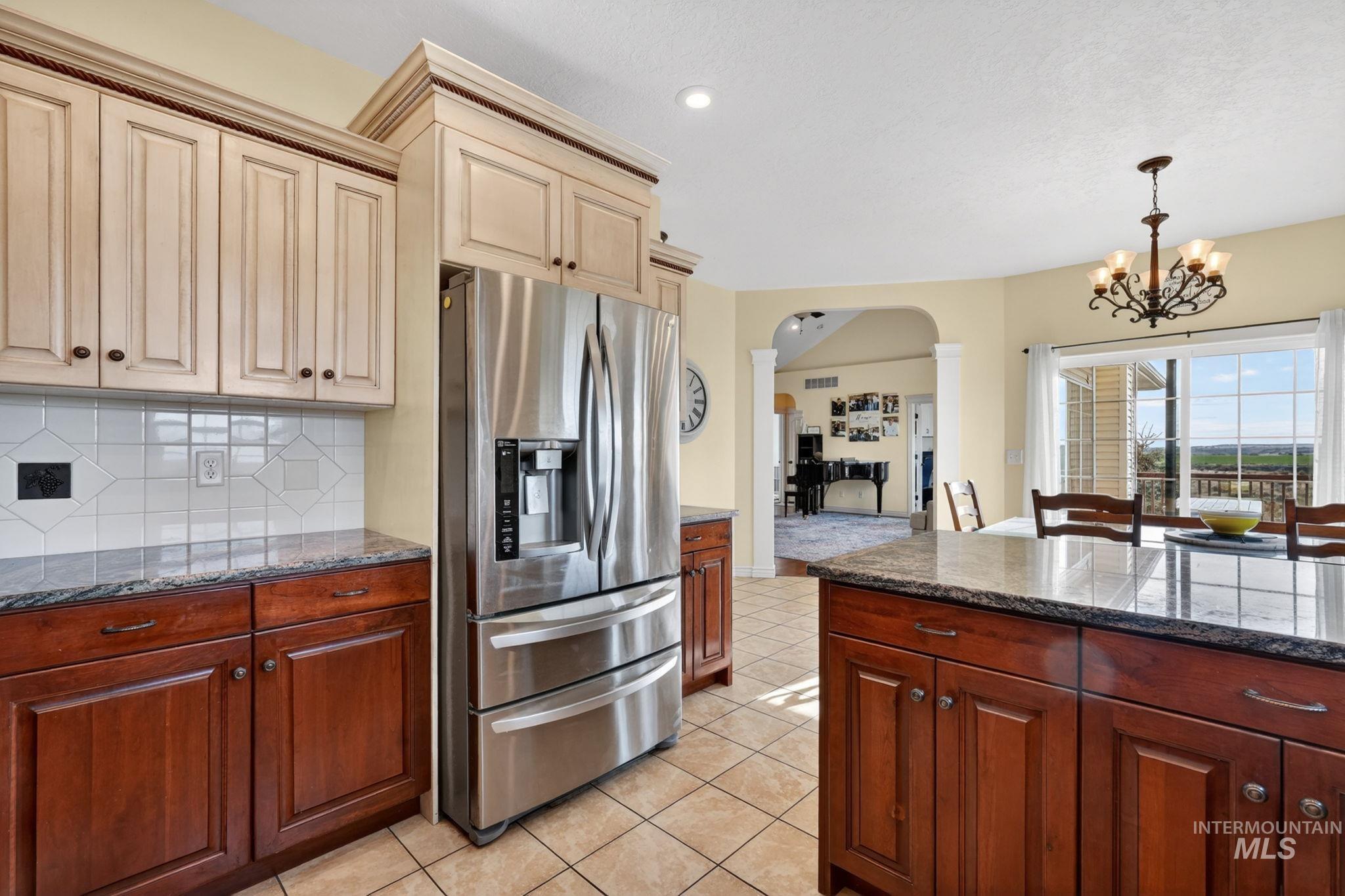 3352 Neeley Road American Falls, ID 83211 - Photo 13 of 43 Kitchen featuring a stainless steel French door refrigerator, two-tone cabinetry, tiled backsplash, and granite countertops