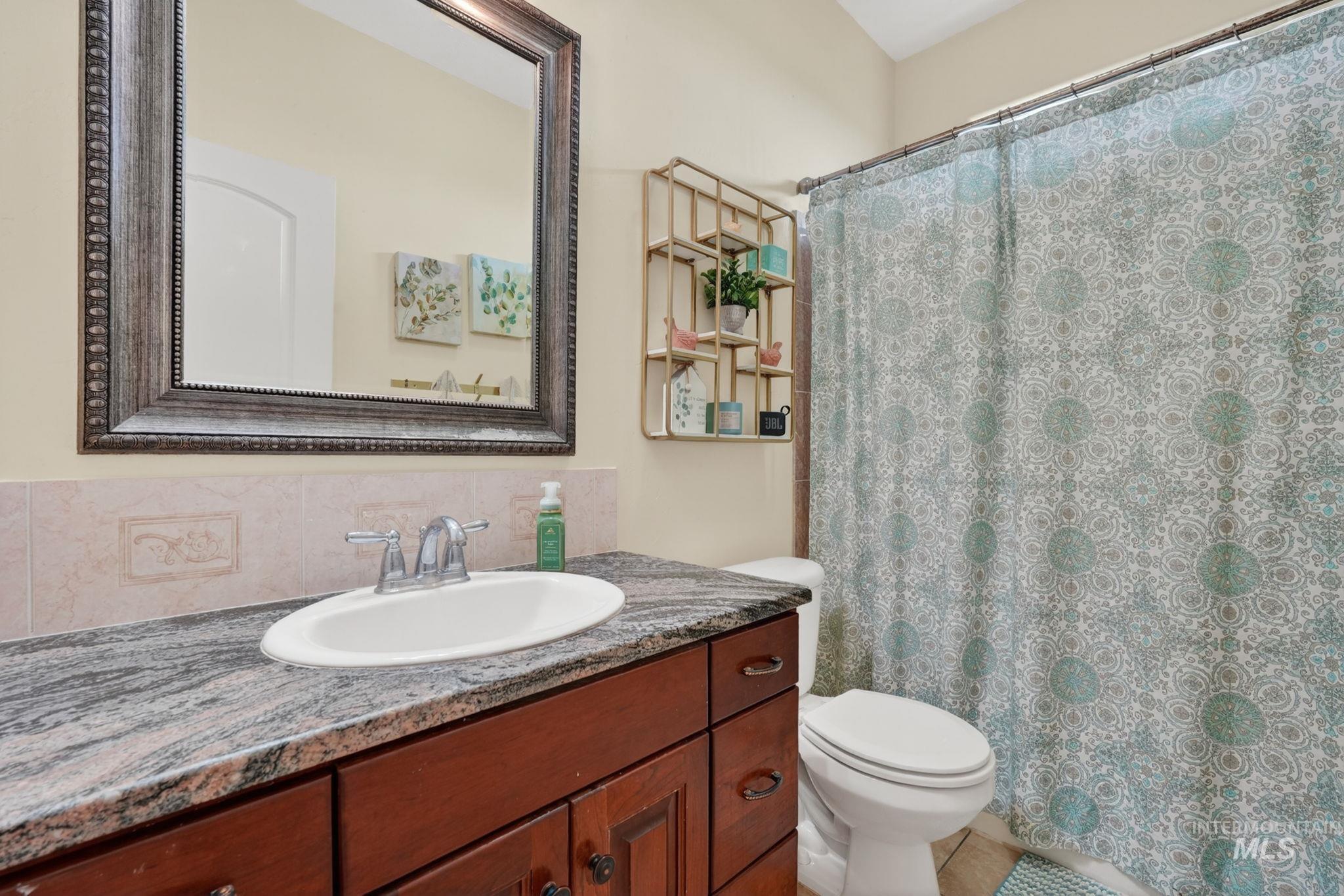 3352 Neeley Road American Falls, ID 83211 - Photo 20 of 43 Bathroom vanity with a dark wood finish, an undermount sink, and a stone countertop