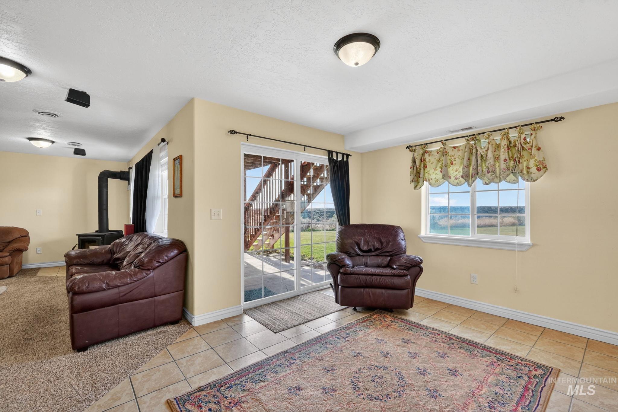 3352 Neeley Road American Falls, ID 83211 - Photo 21 of 43 Spacious interior featuring a wood-burning stove, tile flooring, and a sliding glass door providing exterior access