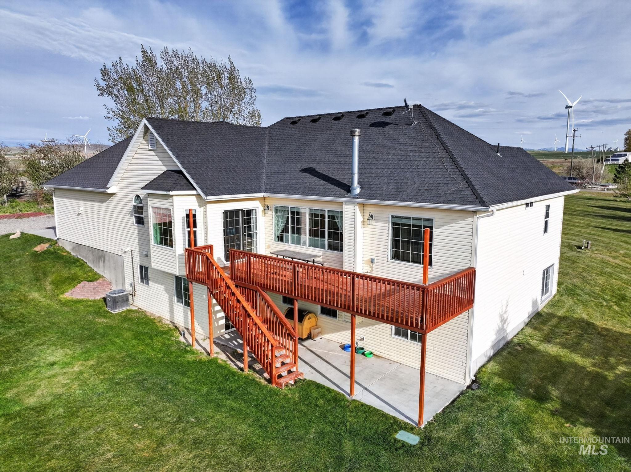 3352 Neeley Road American Falls, ID 83211 - Photo 28 of 43 Rear exterior featuring an elevated wood deck with stairs, lower-level patio, multiple windows, and a dark shingle roof