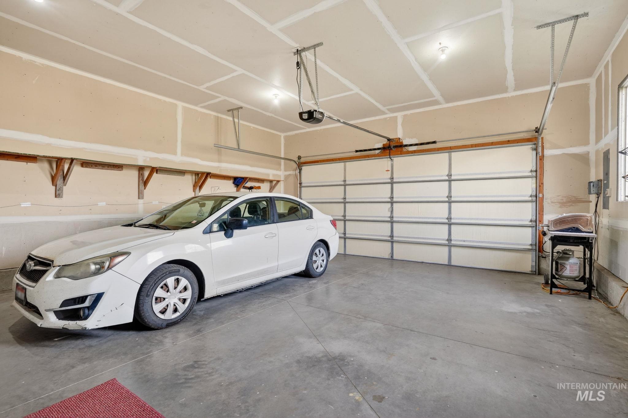 3352 Neeley Road American Falls, ID 83211 - Photo 29 of 43 Spacious garage featuring a concrete floor, an overhead door with an automatic opener, and exposed ceiling joists