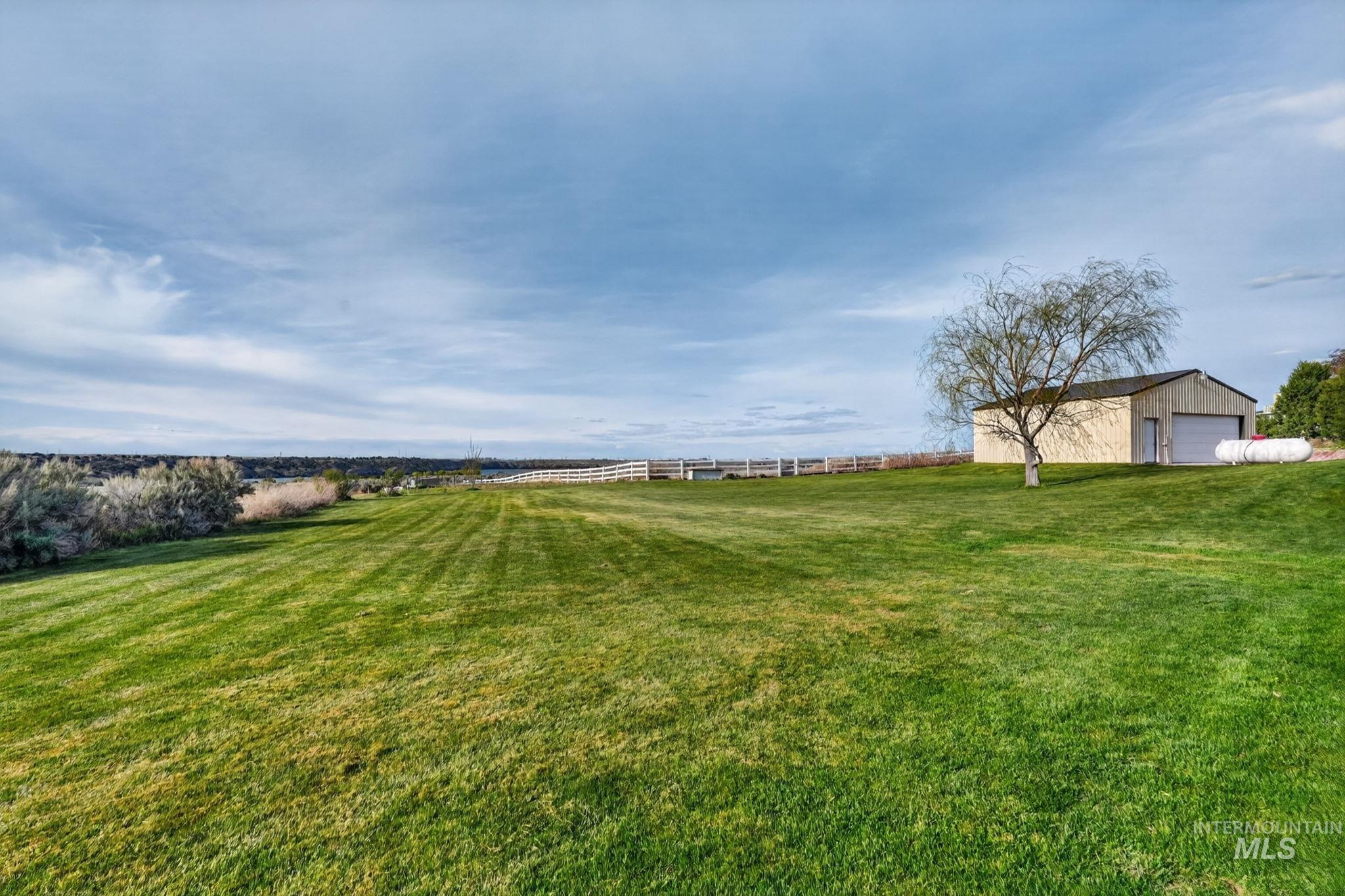 3352 Neeley Road American Falls, ID 83211 - Photo 31 of 43 Expansive green lawn with a white post-and-rail fence, backed by a distant landscape
