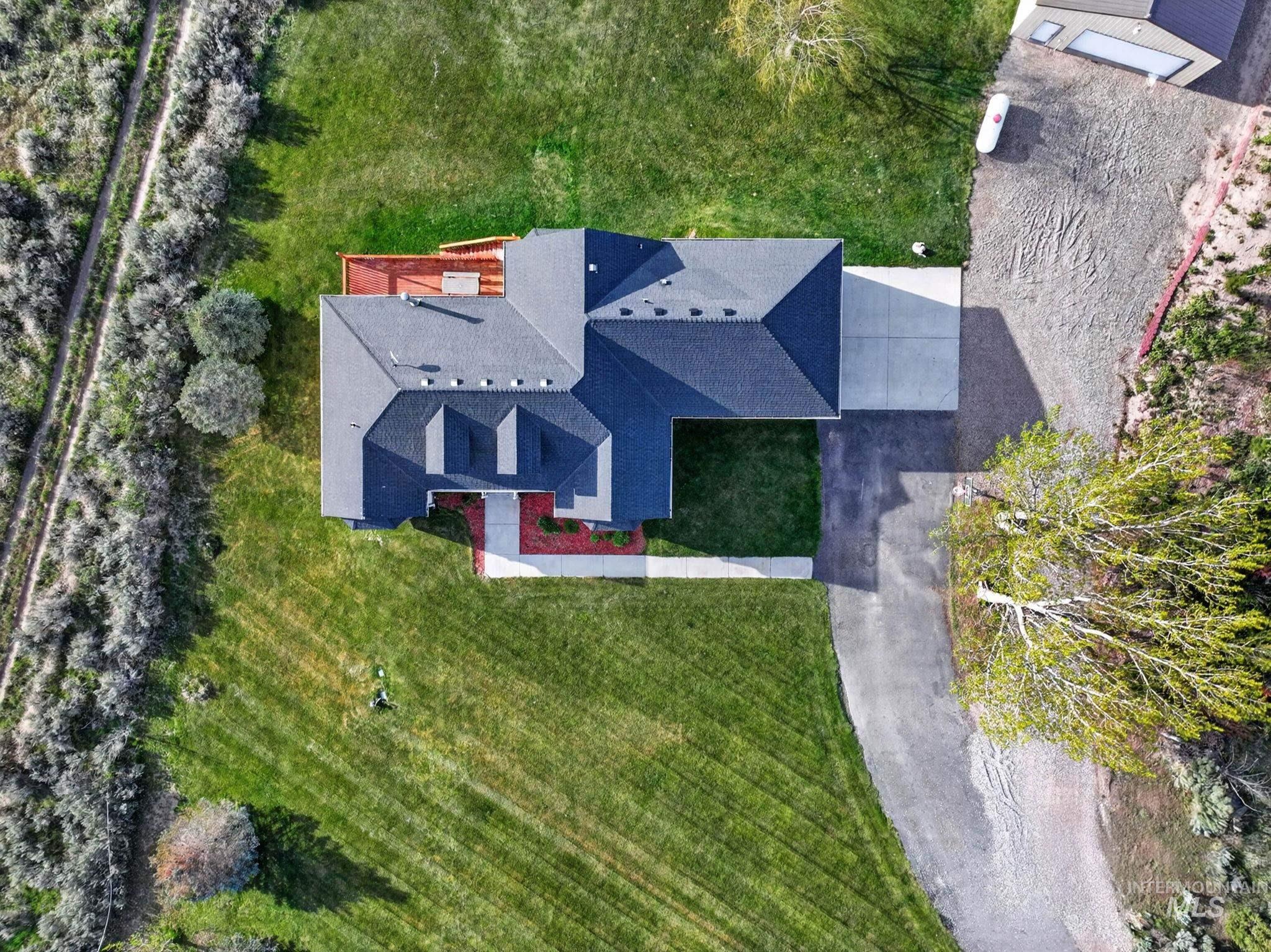 3352 Neeley Road American Falls, ID 83211 - Photo 41 of 43 Expansive property featuring a dark shingle roof, a concrete driveway, an attached garage, a large manicured lawn, and a back deck