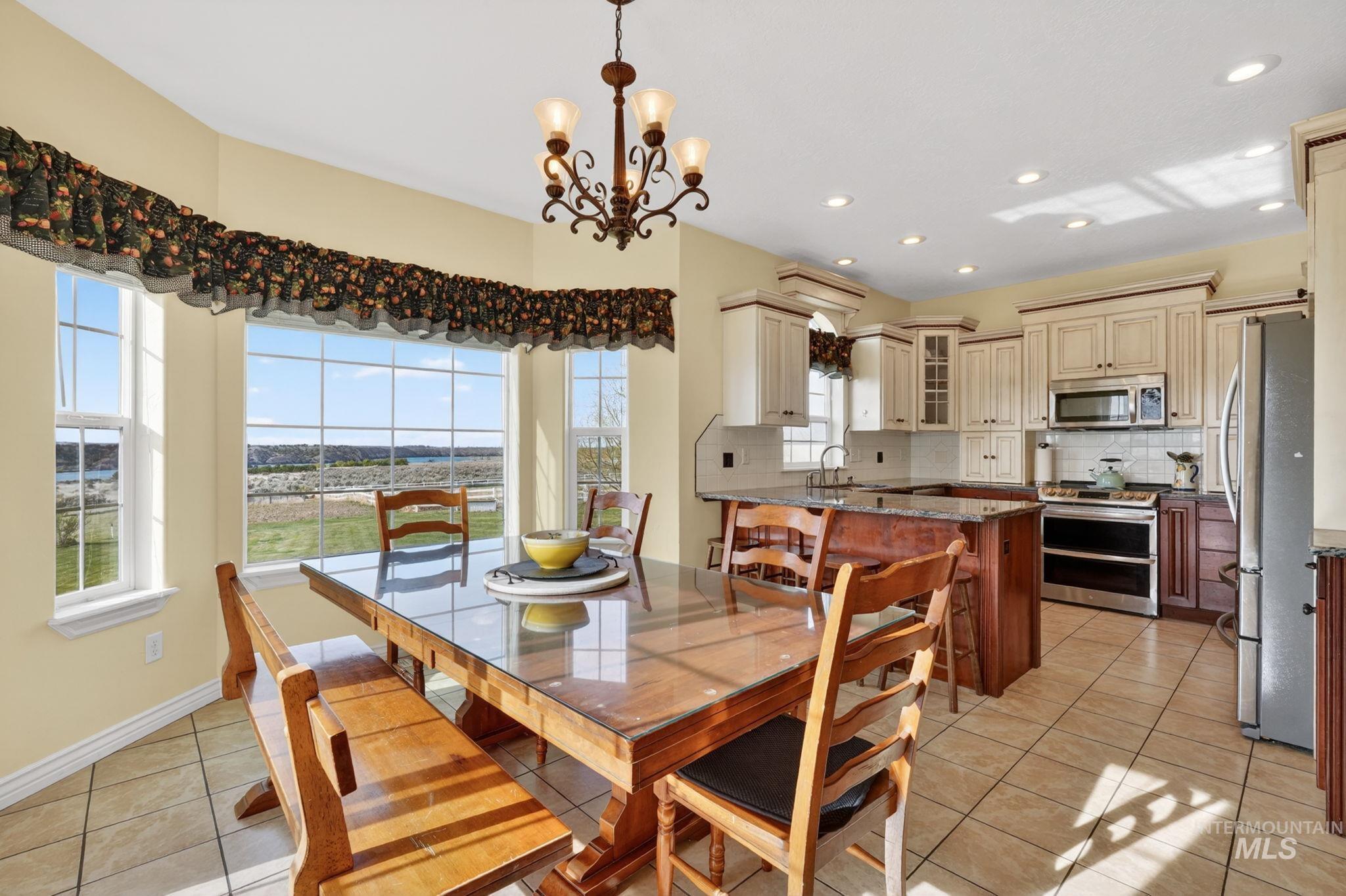 3352 Neeley Road American Falls, ID 83211 - Photo 8 of 43 Kitchen with an integrated dining area featuring a bay window, tiled flooring, white cabinetry, dark wood island with countertop, and stainless steel appliances