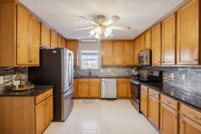 a kitchen with stainless steel appliances granite countertop a refrigerator a sink dishwasher a stove top oven a refrigerator with wooden floor