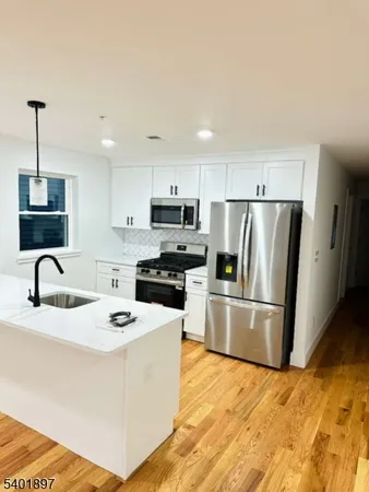 a kitchen with stainless steel appliances granite countertop a refrigerator a stove a sink a microwave and a refrigerator