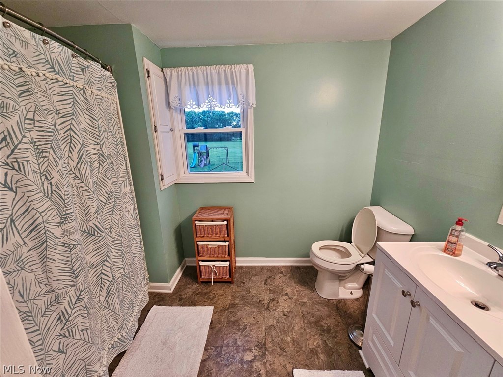 6620 West Lake Road Vermilion, OH 44089 - Photo 21 of 34 Bathroom featuring a white vanity with an integrated sink, a toilet, a window with white shutters, and wood-finish flooring
