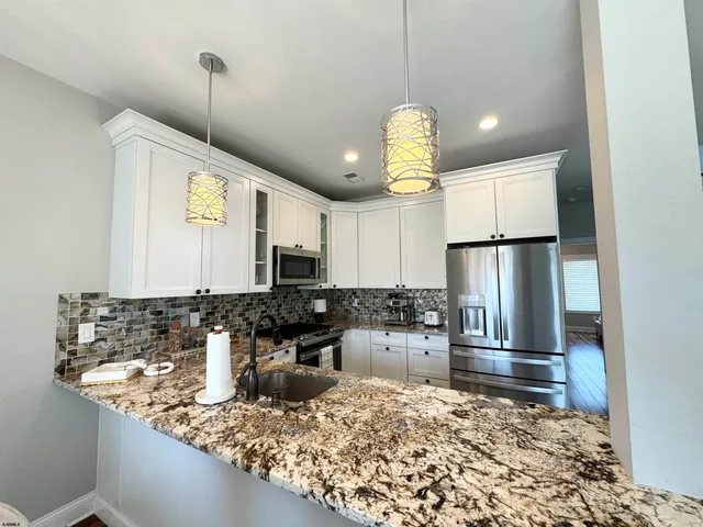 a kitchen with stainless steel appliances granite countertop a stove a sink dishwasher a refrigerator and a oven with wooden floor