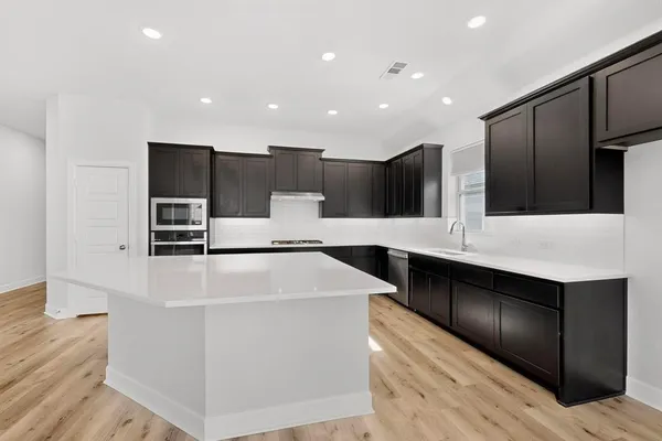 a large kitchen with stainless steel appliances a large counter top and oven