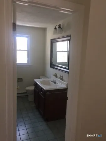 a bathroom with a granite countertop sink toilet and mirror