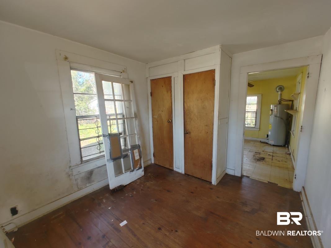1706 Lomeroy Street Mobile, AL 36604 - Photo 24 of 24 Unfurnished bedroom with multiple closets, french doors, water heater, and dark wood-type flooring