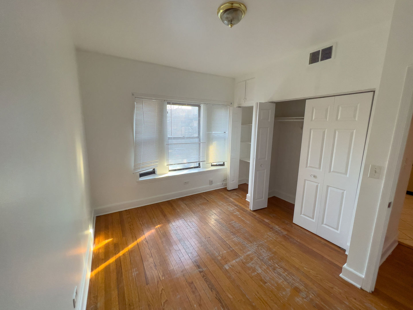 115 East 60th Street, Unit 2 Chicago, IL 60637 - Photo 11 of 11 an empty room with wooden floor cabinet and windows
