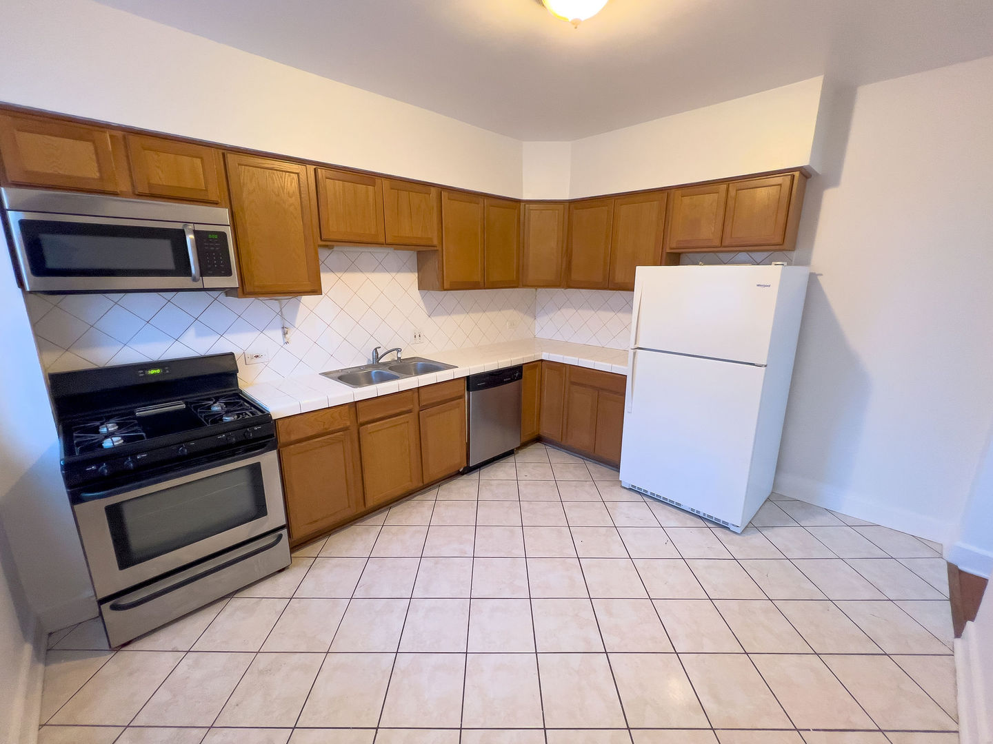 115 East 60th Street, Unit 2 Chicago, IL 60637 - Photo 3 of 11 a kitchen with a sink a stove top oven and cabinets