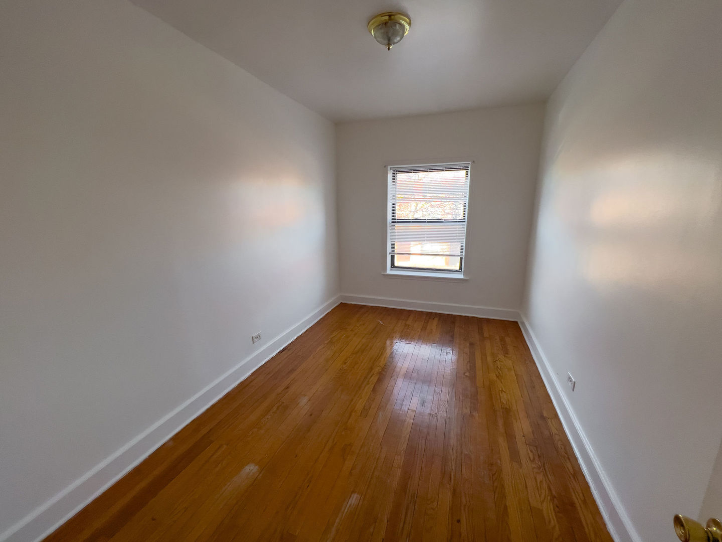 115 East 60th Street, Unit 2 Chicago, IL 60637 - Photo 7 of 11 an empty room with wooden floor and windows