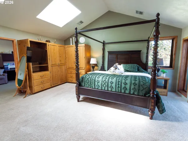 a bedroom with a bed and a flat tv screen on dresser