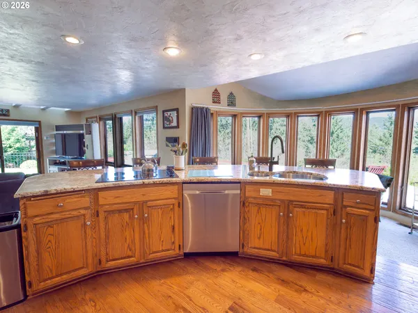 a large kitchen with kitchen island granite countertop a large window a sink and stainless steel appliances
