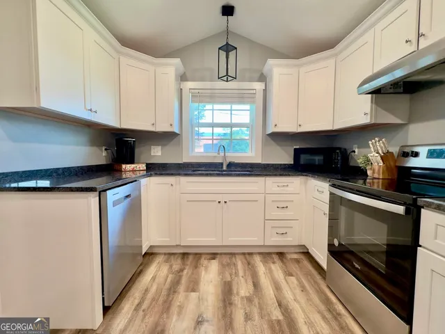 a kitchen with granite countertop a sink stainless steel appliances and cabinets