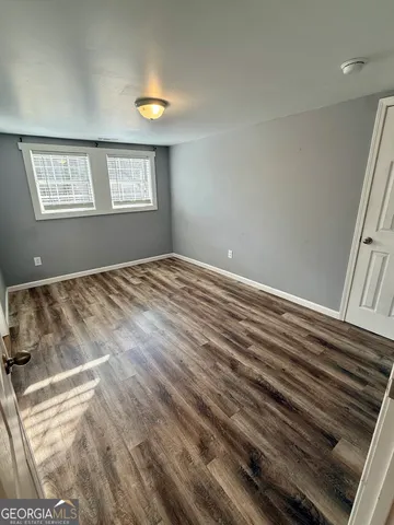 an empty room with wooden floor and ceiling fan