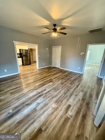 a view of a livingroom with a chandelier fan and wooden floor