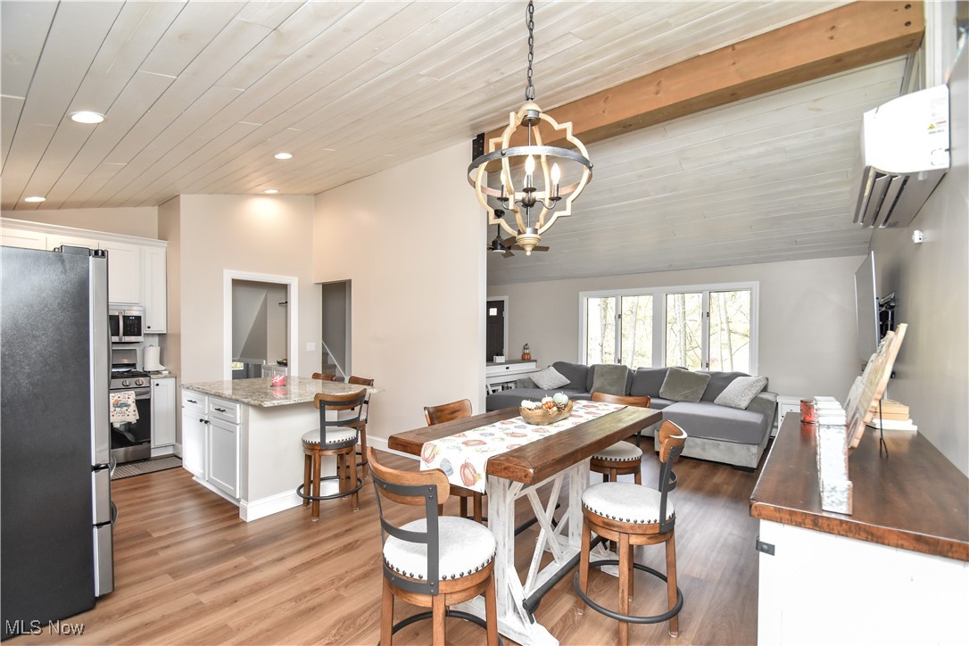631 Carson Salt Springs Road Warren, OH 44481 - Photo 10 of 39 Dining space featuring wood ceiling, hardwood / wood-style floors, an inviting chandelier, vaulted ceiling, and an AC wall unit