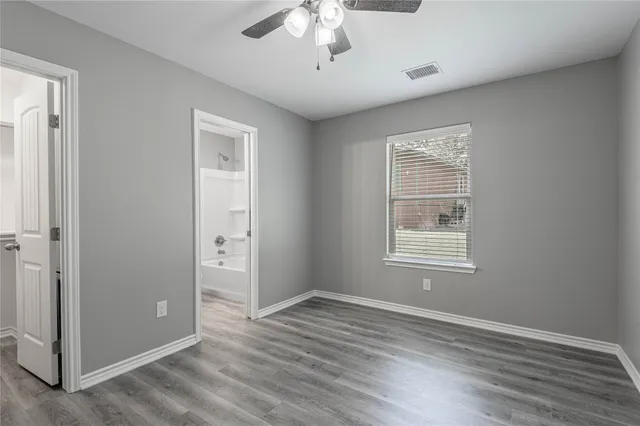 an empty room with wooden floor chandelier and windows