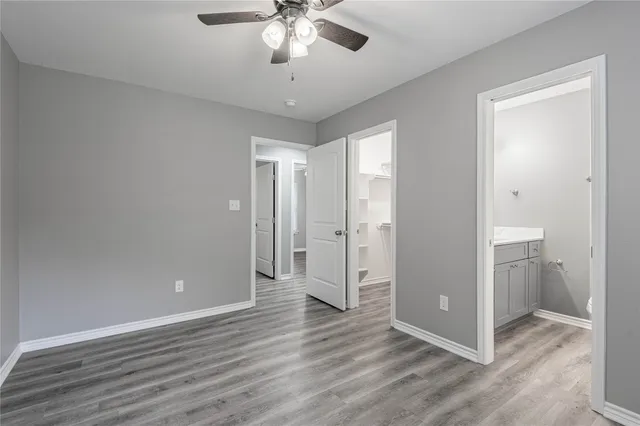 an empty room with wooden floor and ceiling fan