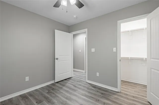 an empty room with wooden floor and chandelier fan