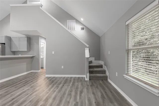 a view of a livingroom with wooden floor and stairs