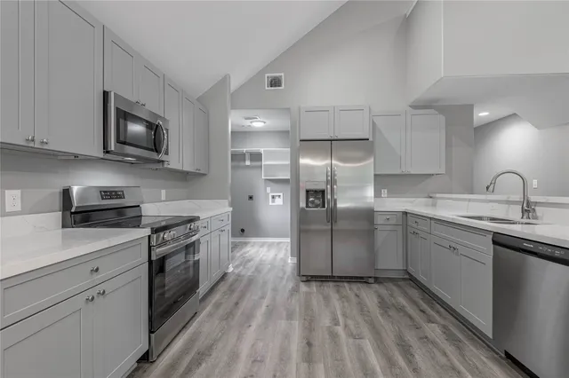 a kitchen with granite countertop a sink stainless steel appliances and white cabinets