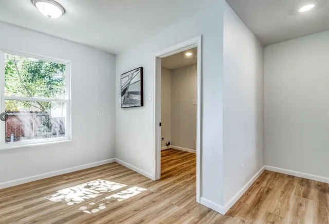 a view of hallway with window and wooden floor
