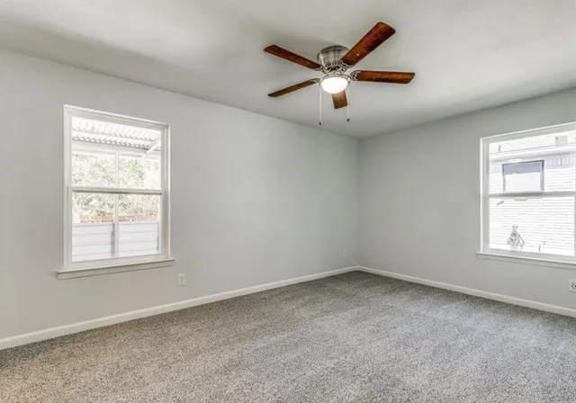 an empty room with window and ceiling fan