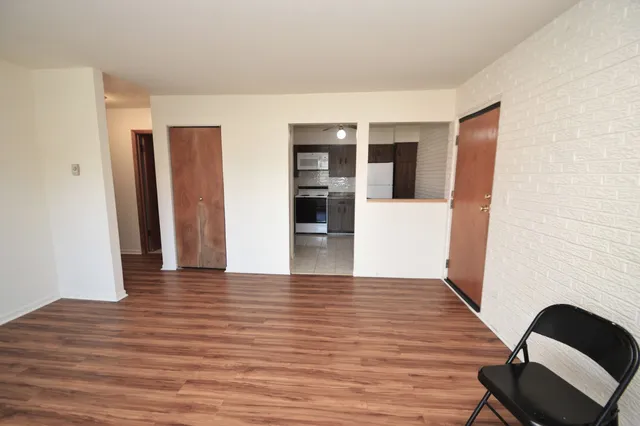 a view of an empty room with wooden floor and closet