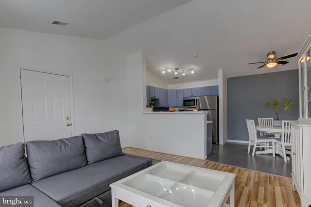 a living room with furniture and a dining table with wooden floor
