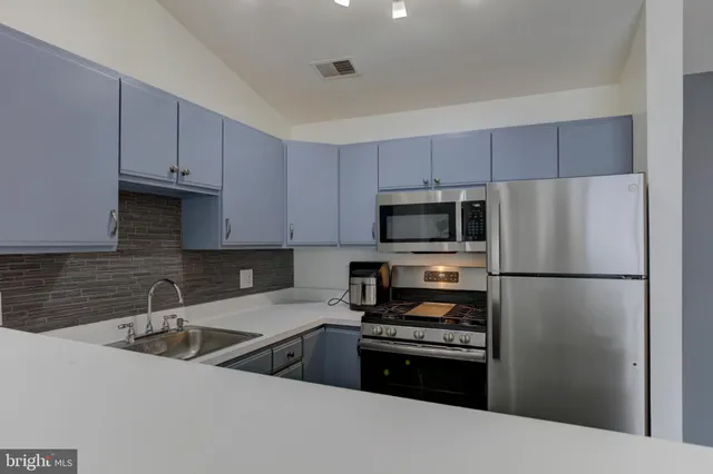 a kitchen with stainless steel appliances a refrigerator a sink a stove a microwave and cabinets