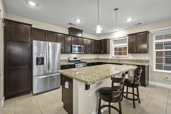 a kitchen with stainless steel appliances granite countertop a refrigerator a stove a sink a microwave and a refrigerator