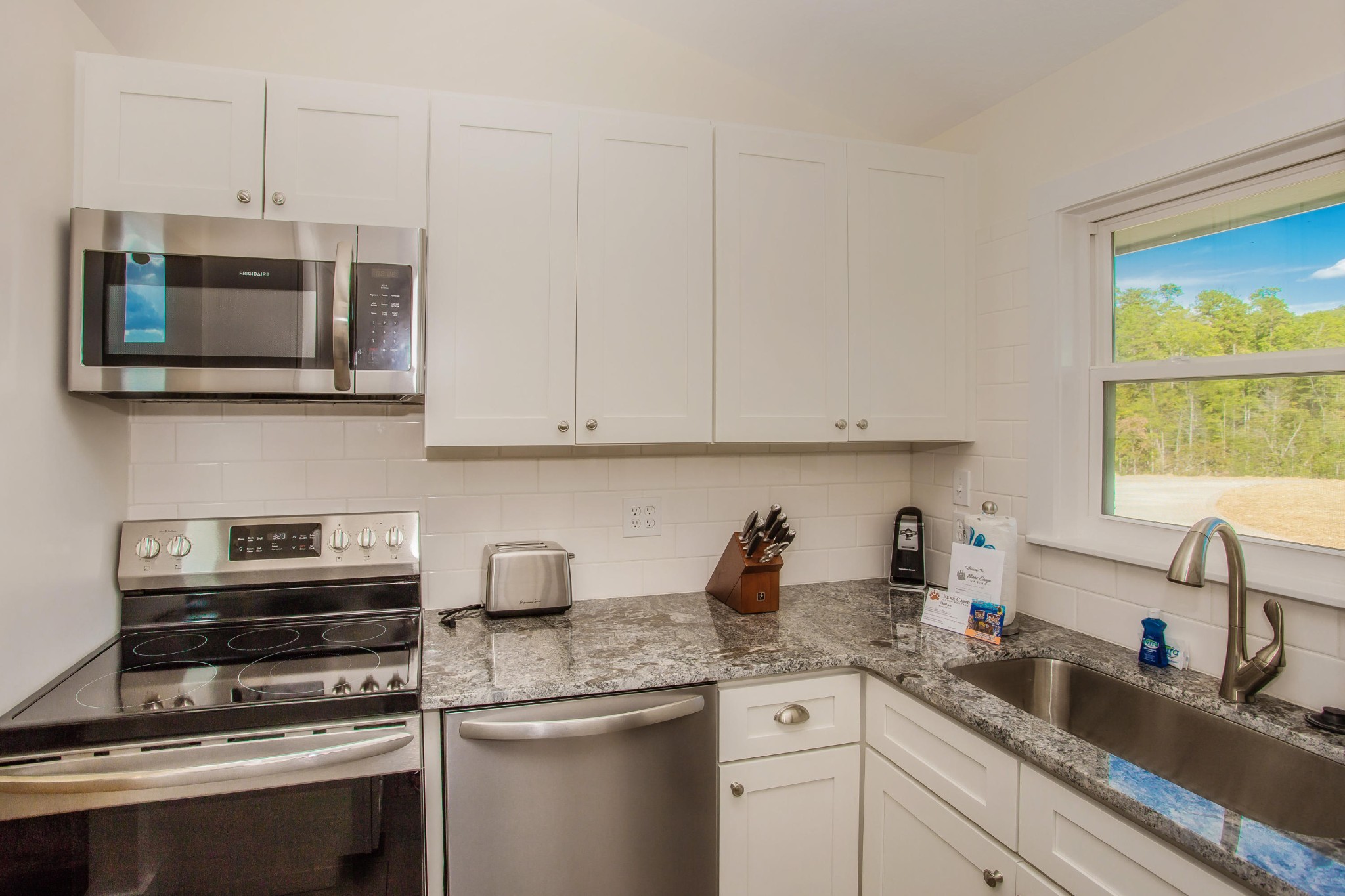3202 Hickey Road Sevierville, TN 37876 - Photo 10 of 28 a kitchen with stainless steel appliances granite countertop a sink a microwave a stove and white cabinets
