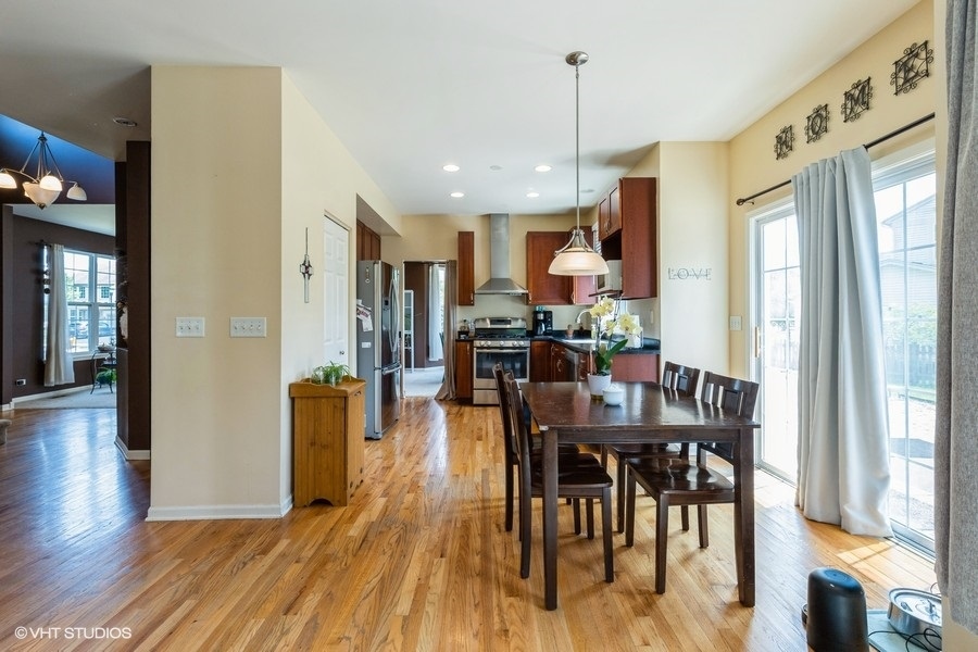 9675 Newton Road Huntley, IL 60142 - Photo 6 of 18 a view of a dining room and livingroom with furniture wooden floor a chandelier