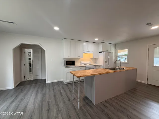 a kitchen with stainless steel appliances granite countertop a lot of counter space and wooden floor