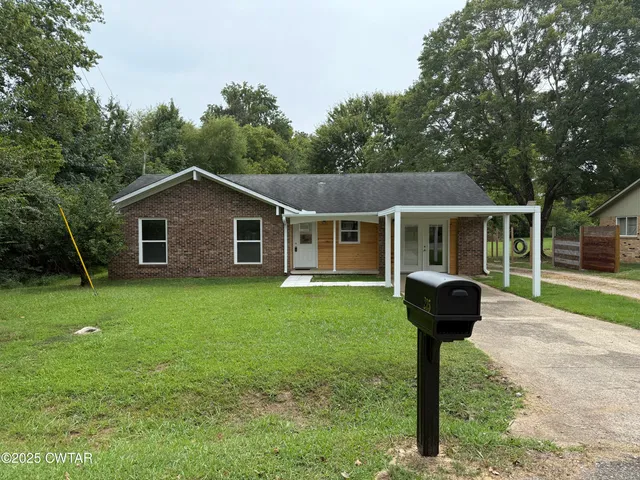 a front view of a house with a yard and tree