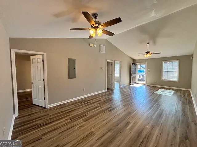 a view of an empty room with wooden floor and a window