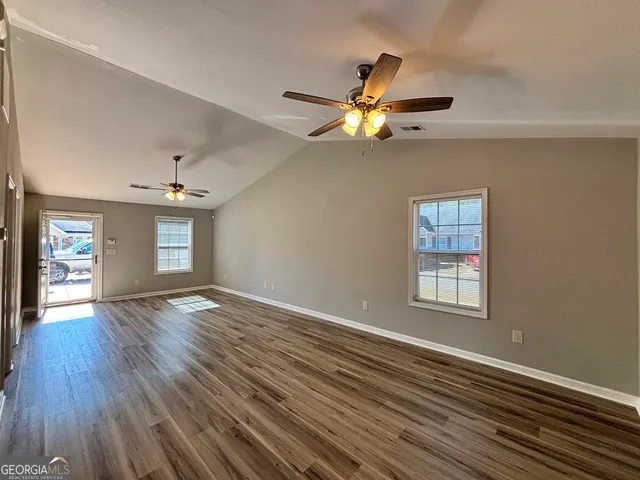 a view of an empty room with a window and wooden floor
