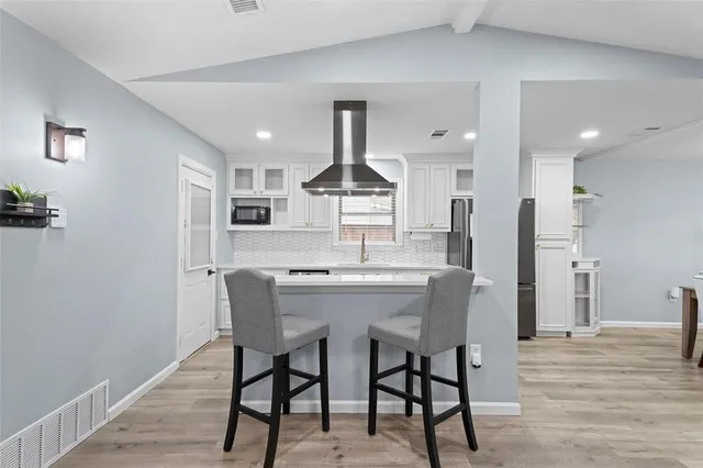 a kitchen with stainless steel appliances a dining table chairs and wooden floor