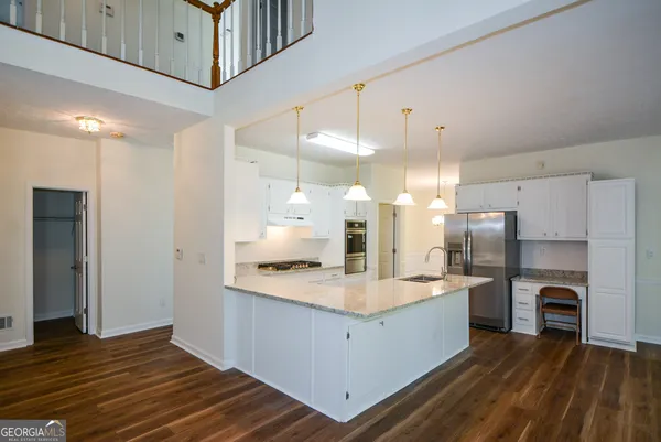 a large kitchen with a large counter top a sink stainless steel appliances and cabinets