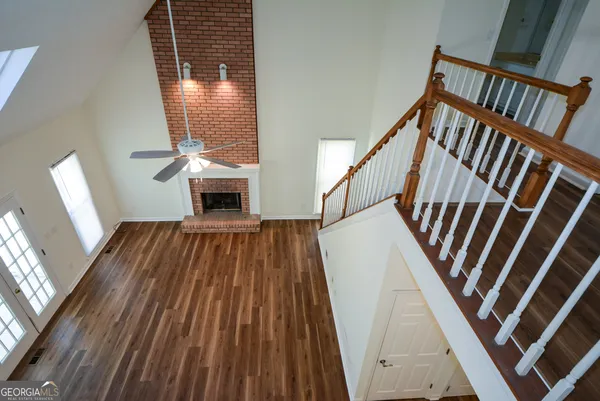 a view of an empty room with wooden floor and a chandelier fan