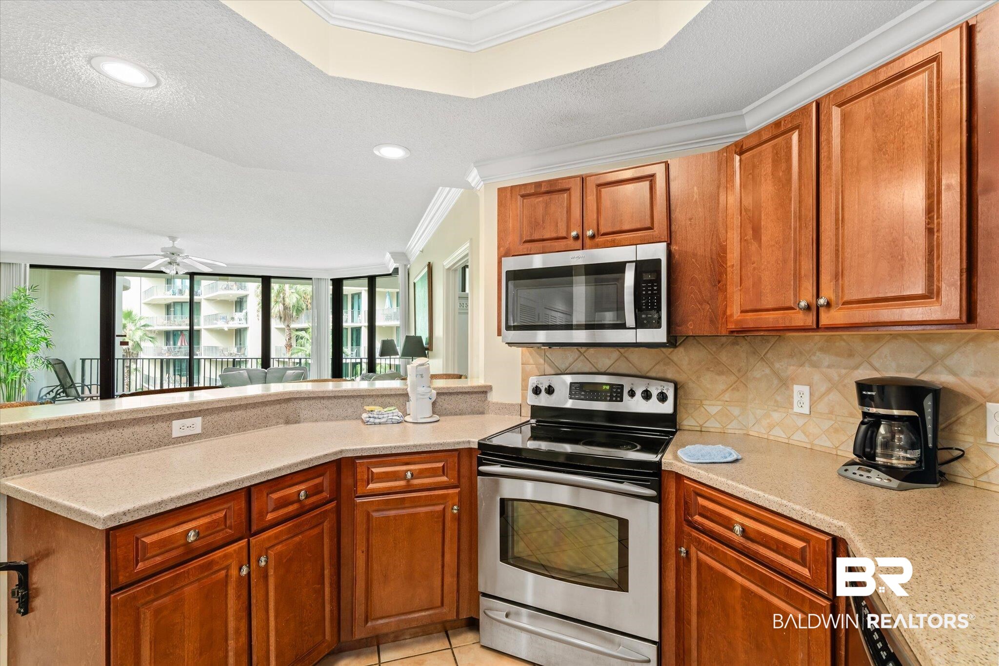 27580 Canal Road, Unit 1322 Orange Beach, AL 36561 - Photo 10 of 30 Kitchen featuring light tile patterned floors, appliances with stainless steel finishes, ceiling fan, decorative backsplash, and ornamental molding