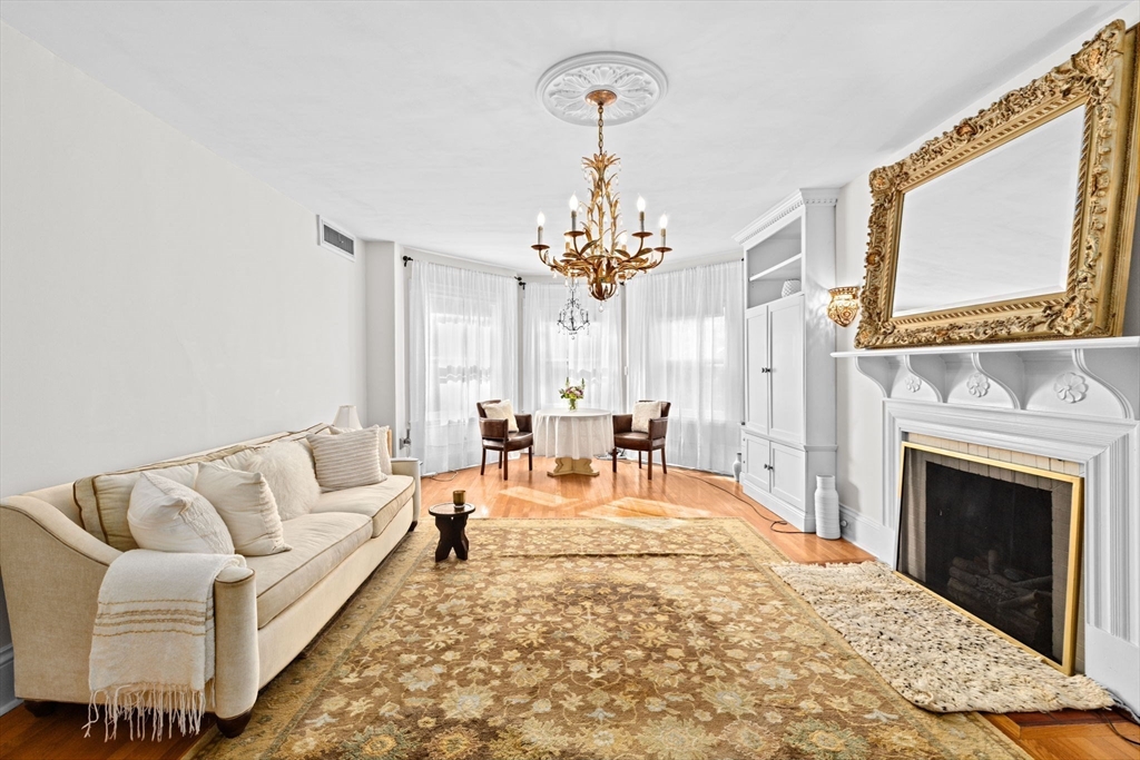 302 Commonwealth Avenue, Unit E Boston, MA 02115 - Photo 2 of 13 a living room with furniture a fireplace and a chandelier